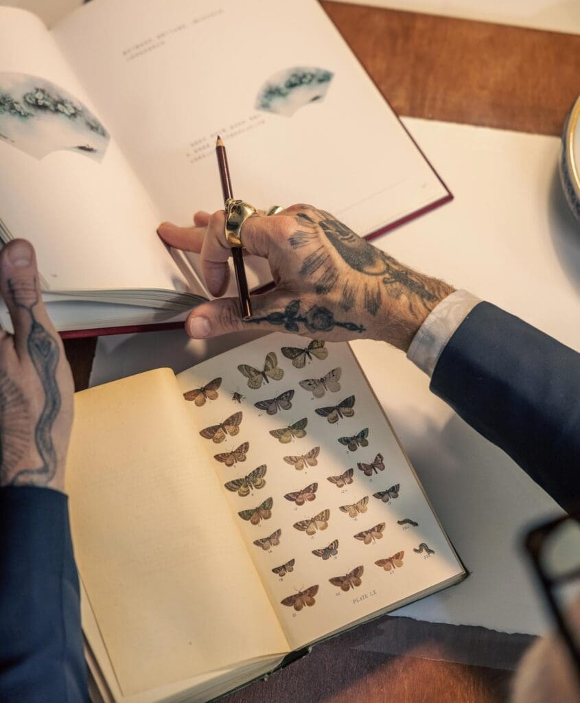 RIOT, NYC Creative Agency: Close-up of Christopher Young’s tattooed hands flipping through a reference book of butterflies Close-up of Christopher Young’s tattooed hands flipping through a reference book of butterflies