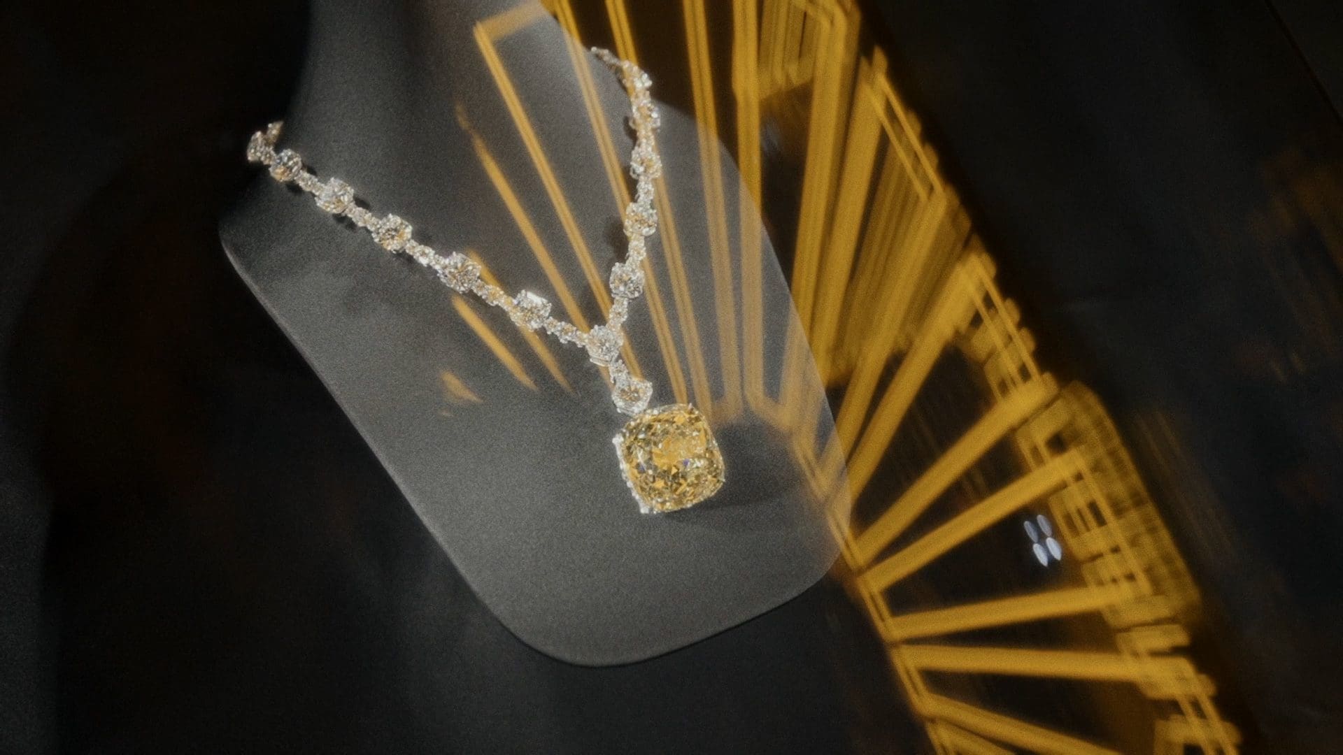 RIOT, NYC Creative Agency: Stunning display of a Tiffany & Co. diamond necklace with a large yellow central diamond, elegantly draped on a mannequin with a radiant reflection of light creating a dynamic backdrop. Stunning display of a Tiffany & Co. diamond necklace with a large yellow central diamond, elegantly draped on a mannequin with a radiant reflection of light creating a dynamic backdrop.
