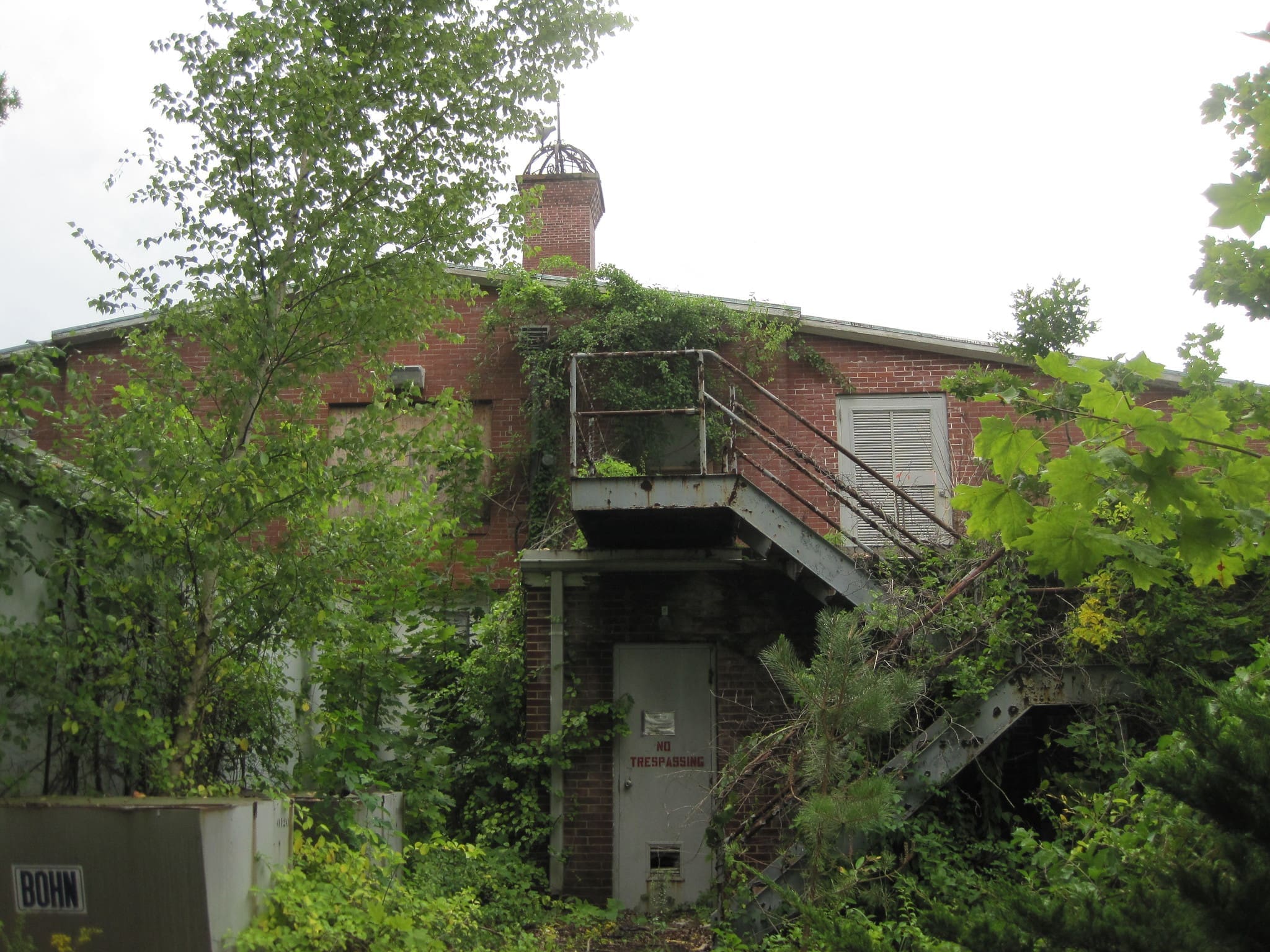 A photograph of the overgrown and abandoned Wardenclyffe Tower site, where Tesla envisioned transmitting wireless energy.