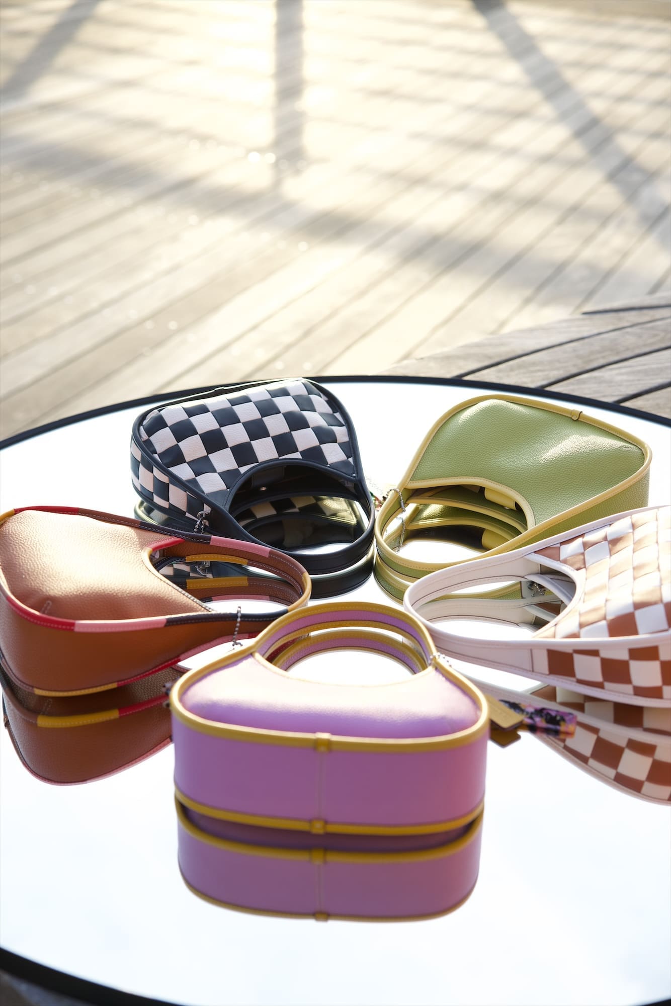 Coachtopia Ergo bags arranged on a round mirror on the boardwalk