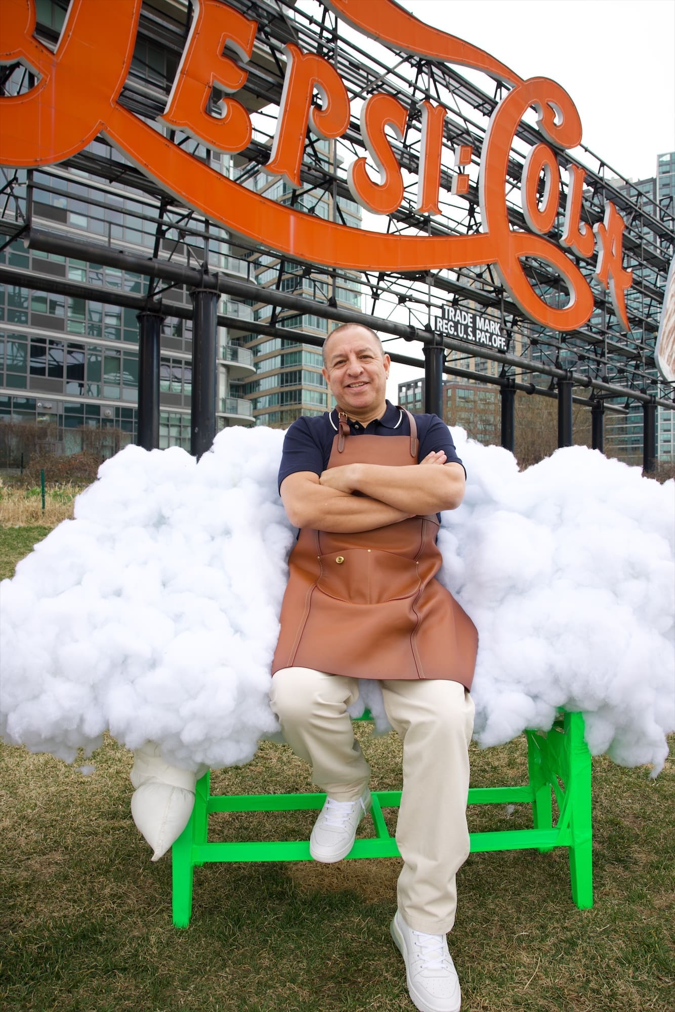 Coach master craftsman Mauricio Alvarado sitting on a cloud of cotton under the Pepsi-Cola sign