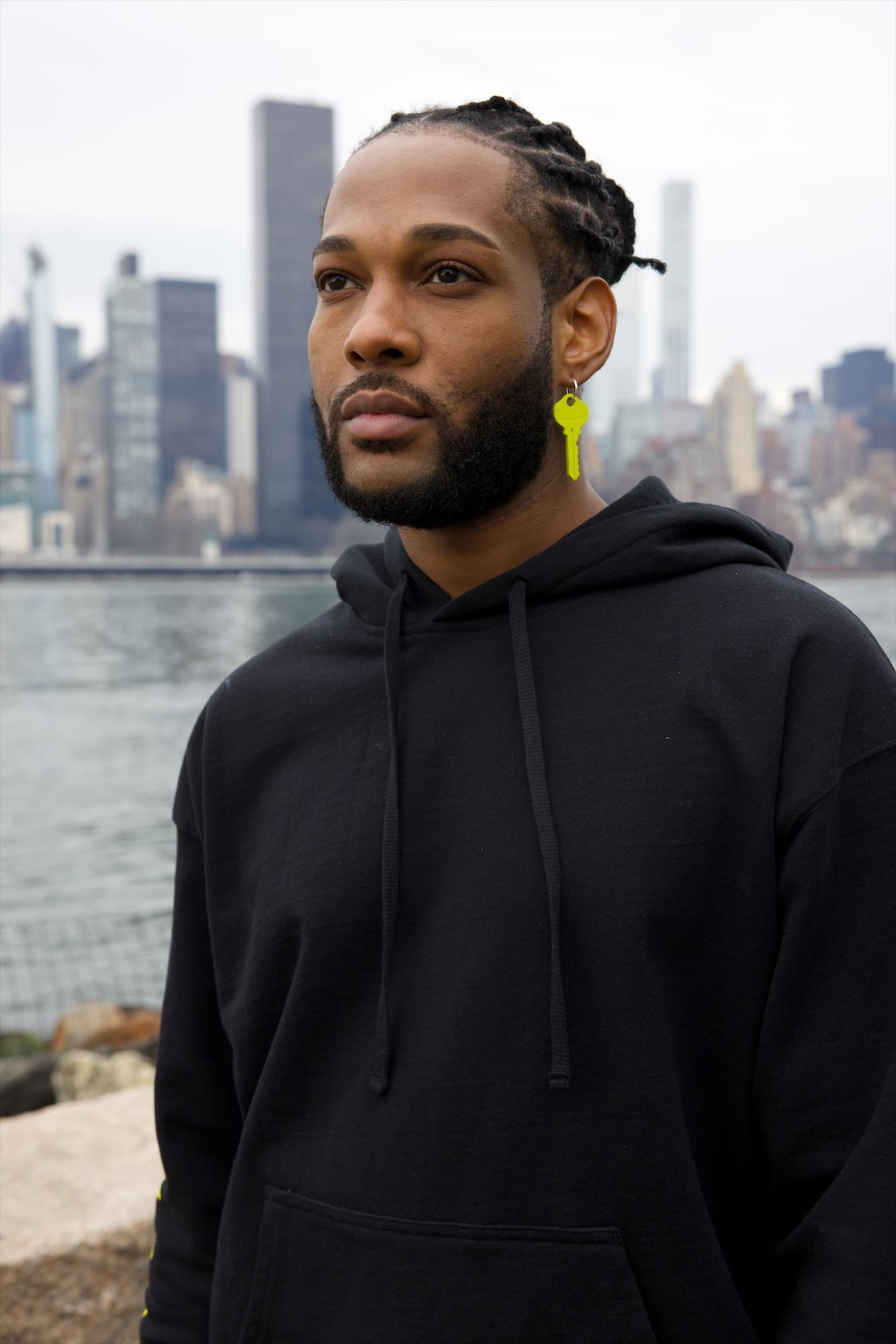 Trey Denis in a black hoodie by the East River