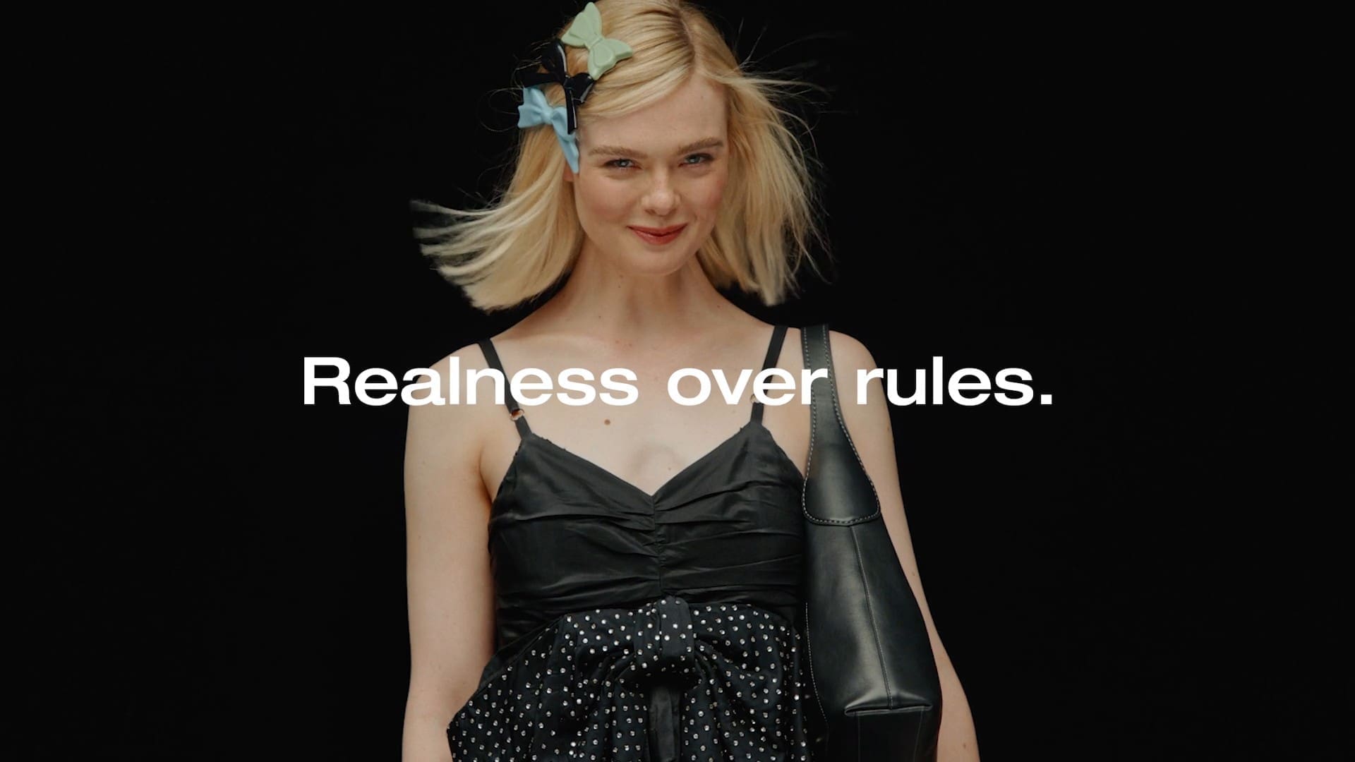 A smiling blonde woman with bow clips in her hair under the line Realness over rules, from the Coach SMC 2025 sizzle