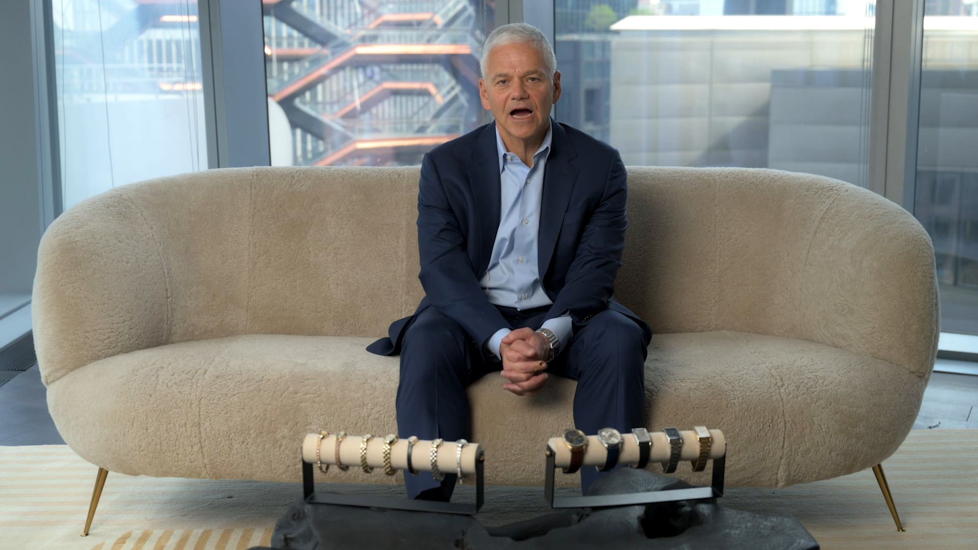 Efraim Grinberg of Movado on a sofa, the Vessel at Hudson Yards behind him