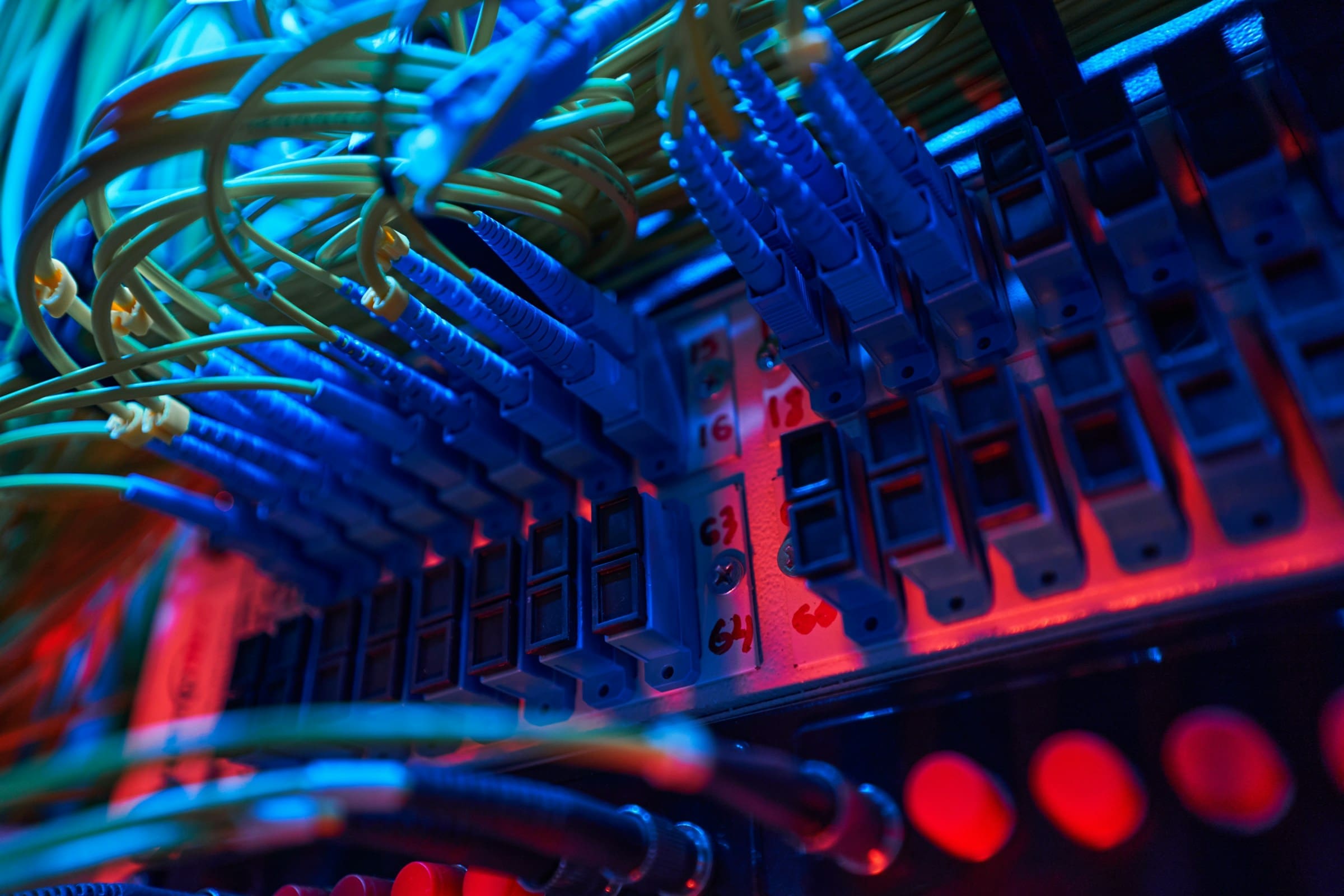 Close-up of glowing fiber optic cables and ports inside a server rack