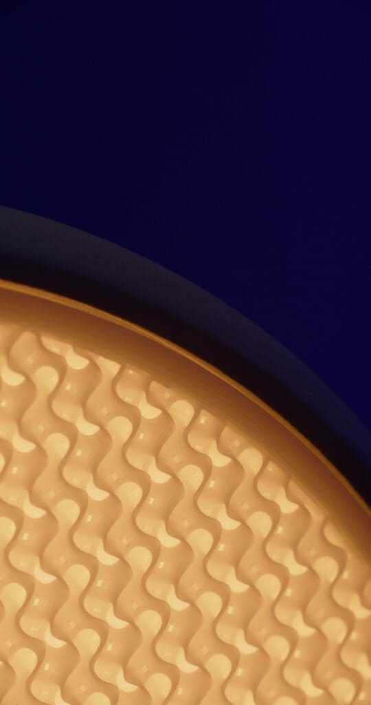 Macro close-up of the rippled 3D-printed texture of the Gantri Stack lamp, lit amber against deep blue