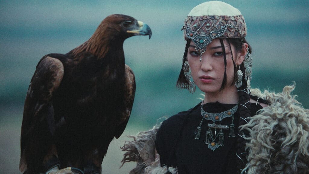 RIOT, NYC Creative Agency: A woman in an embroidered headdress beside a golden eagle by the sea, from the Bleed Electric Gravity music video A woman in an embroidered headdress beside a golden eagle by the sea, from the Bleed Electric Gravity music video