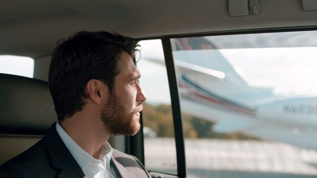 An executive looks out of the car window at a NetJets jet on arrival
