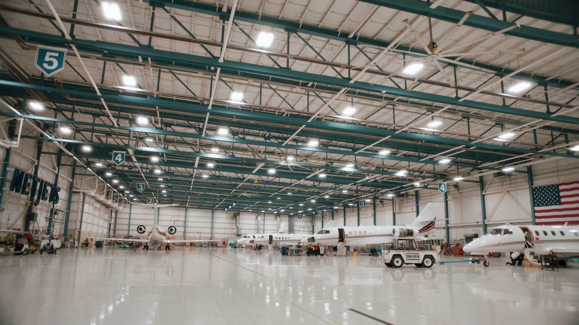 A wide view of the gleaming NetJets hangar in Columbus with jets and an American flag