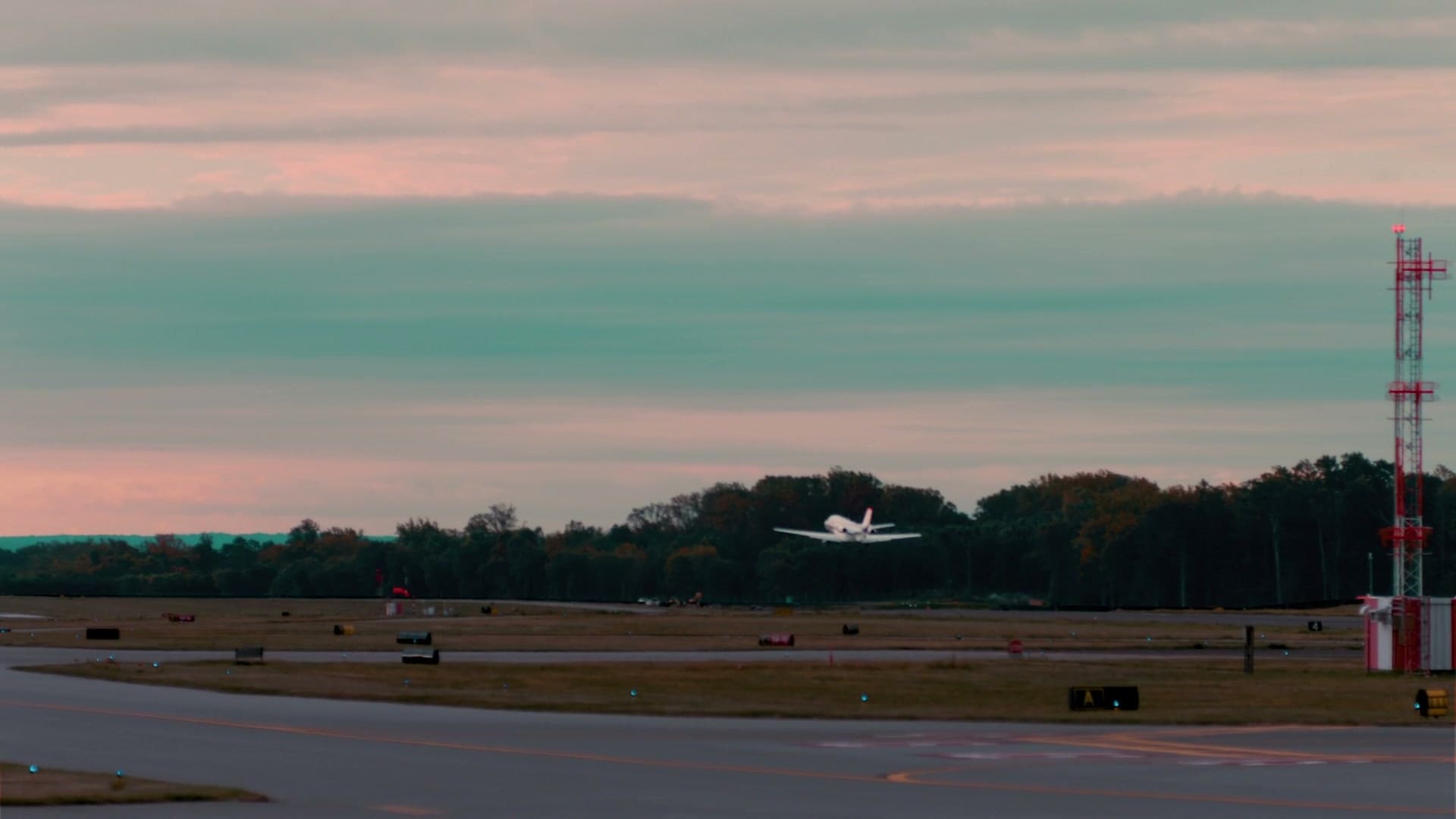 A NetJets jet lifting off the runway into a pink and teal dusk