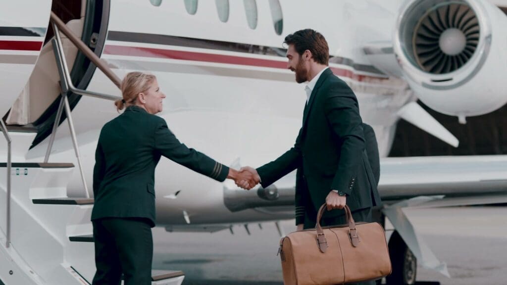 An executive shakes hands planeside beside a NetJets jet, holding a leather bag