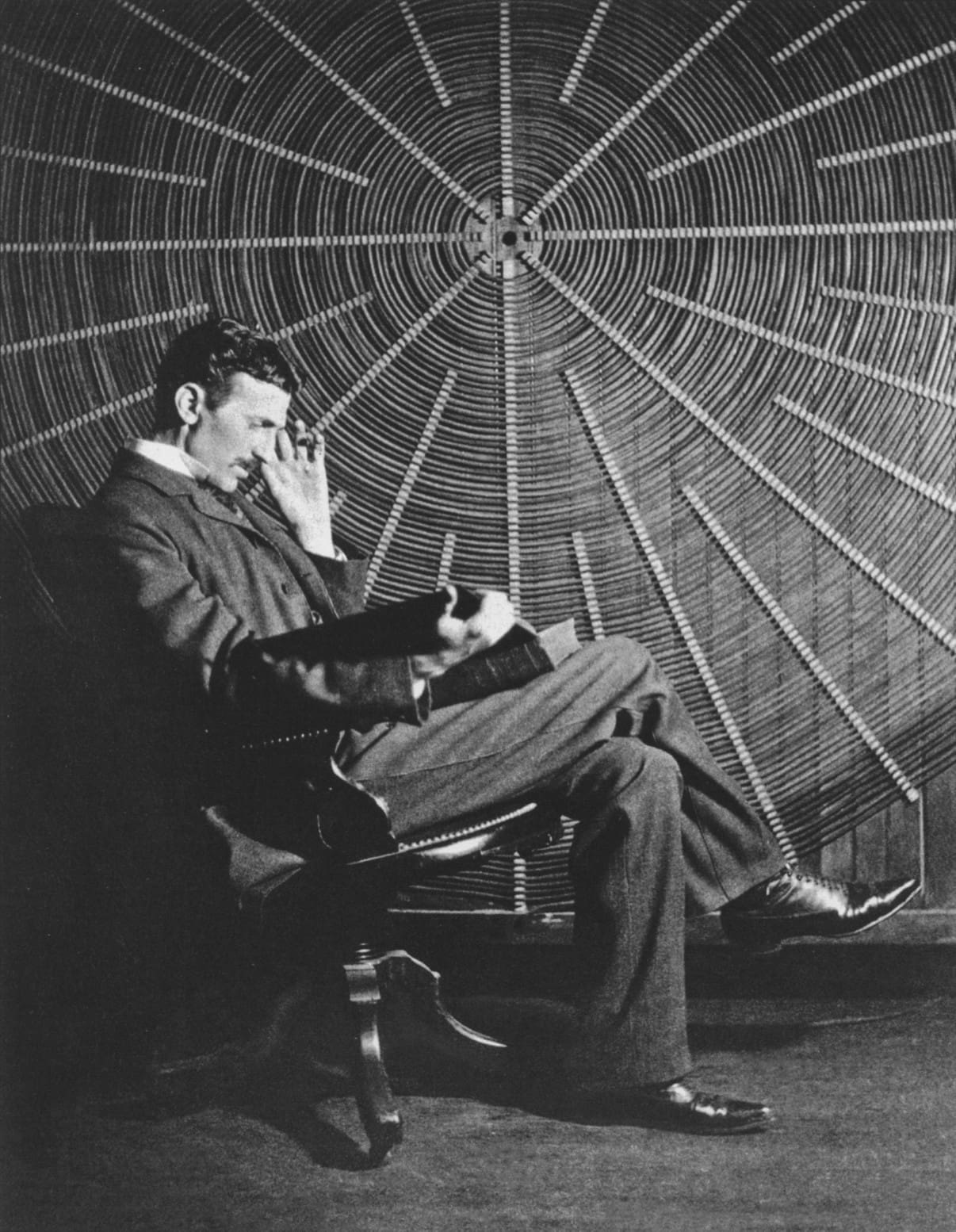 Nikola Tesla sitting in a chair, reading a book, with a large spiral coil in the background, symbolizing his deep thoughts on electricity and the mysteries of the universe.
