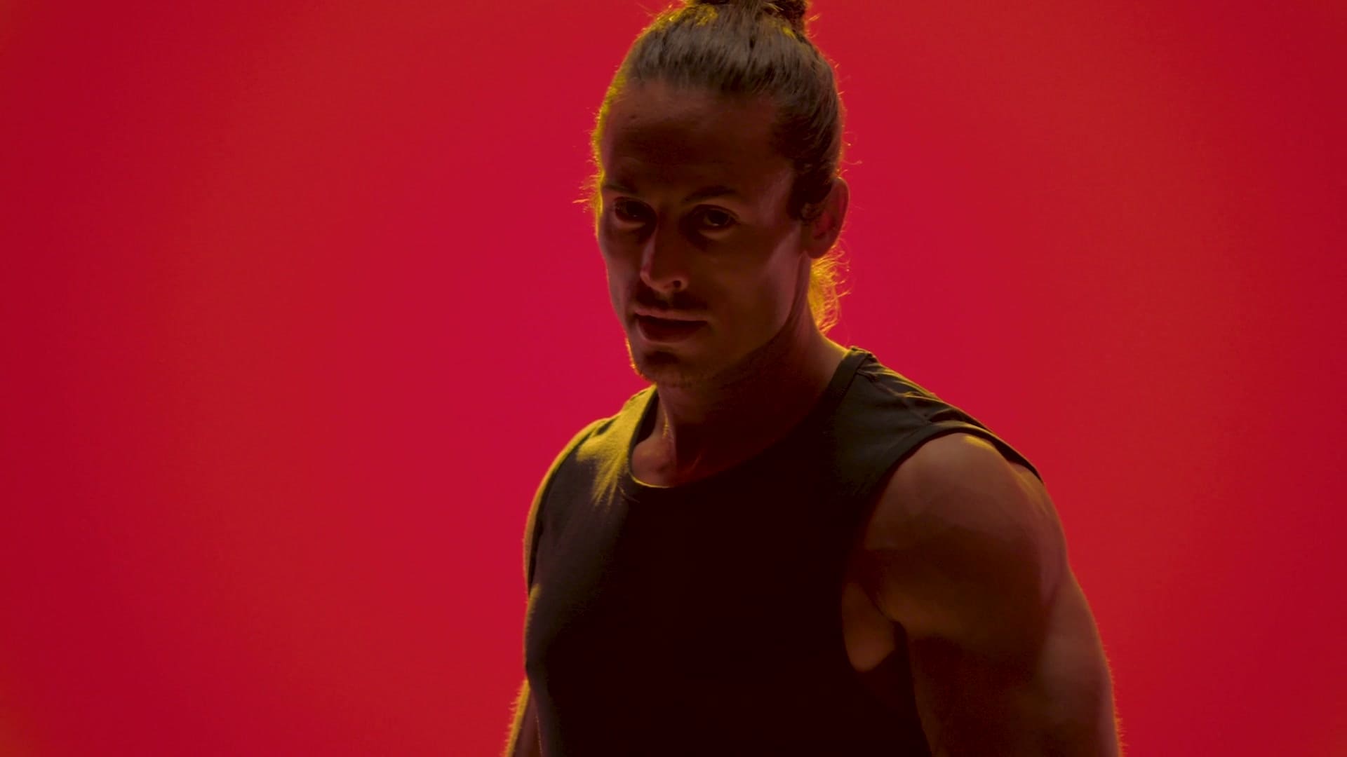 SoulCycle instructor Sam Y looking to camera against a red backdrop