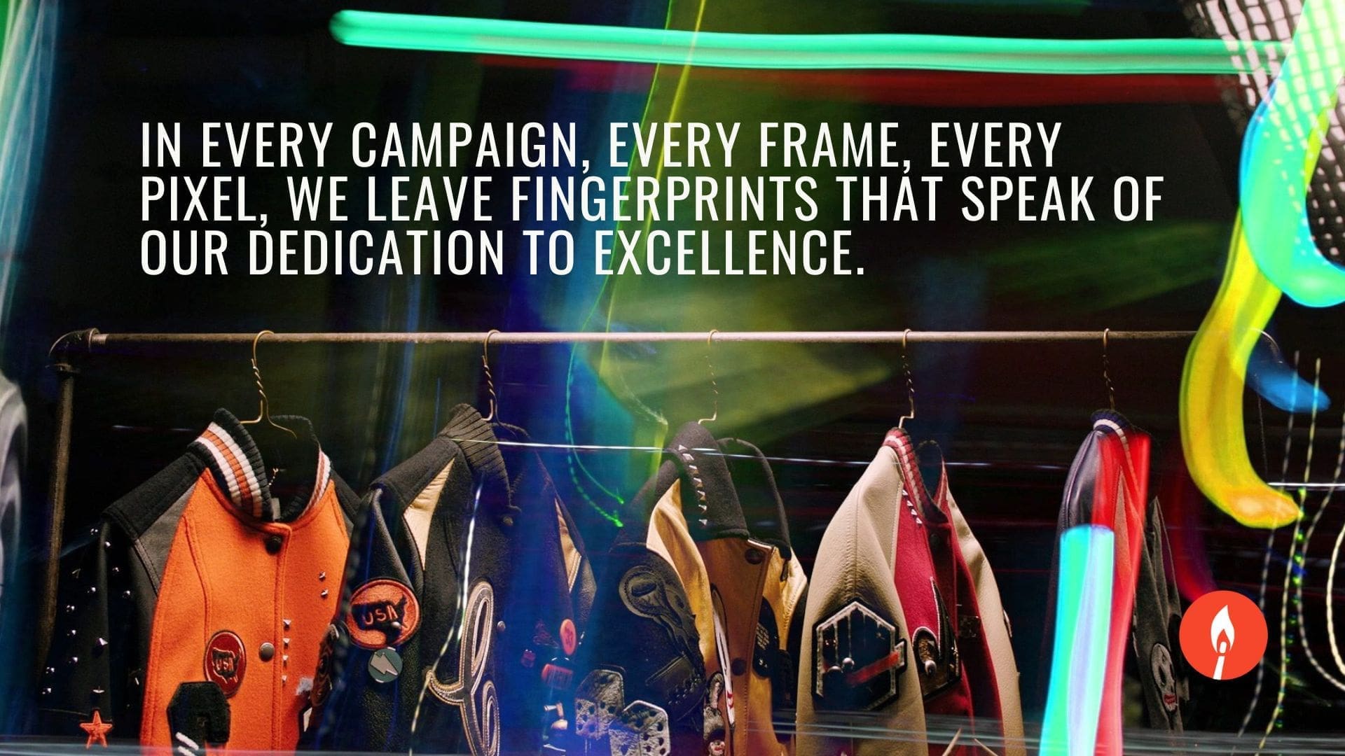 A vibrant image showcasing a row of colorful jackets on a clothing rack, with the text 'In every campaign, every frame, every pixel, we leave fingerprints that speak of our dedication to excellence.' The RIOT logo is displayed below the text.